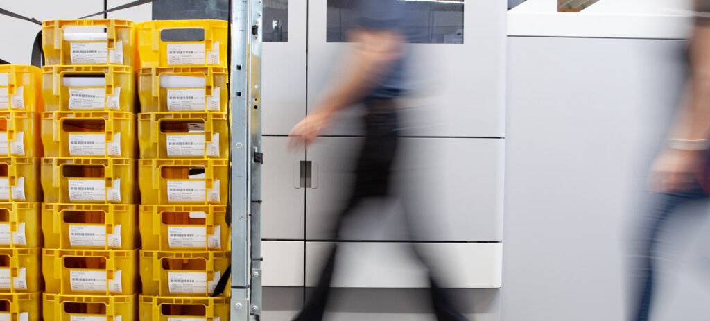 Postboxen in der Produktionshalle mit Menschen verschwommen im Hintergrund