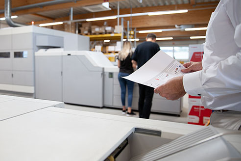 Ein Mitarbeiter kontrolliert das Druckergebnis am Drucker